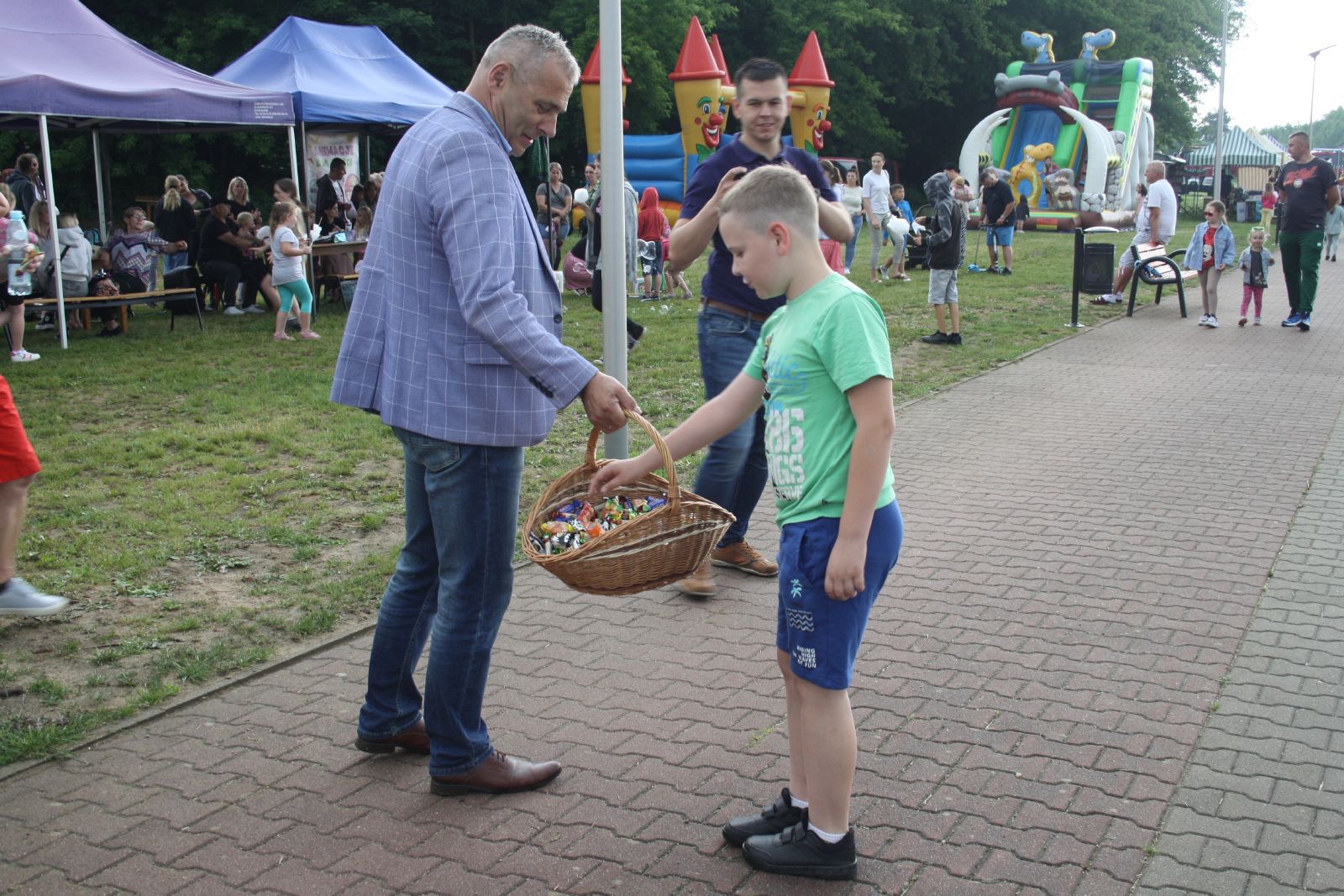 Burmistrz Andrzej Bracha rozdaje cukierki z koszyka wiklinowego, po prawej stronie chłopiec